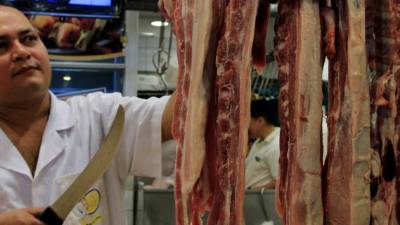 Un empleado de una carnicería de un mercado sampedrano selecciona uno de los cortes para venta.