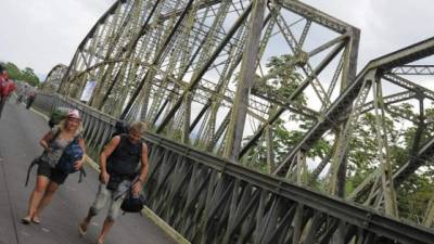 Turistas cruzan el puente binacional centenario sobre el río Sixaola en Sixaola, frontera entre Panamá y Costa Rica. (EFE)