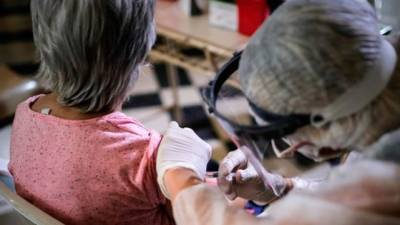 Una enfermera aplica a una mujer una vacuna contra la gripe.