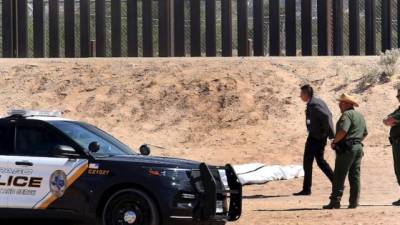 Especialistas forenses de Estados Unidos resguardan el cuerpo de un migrante mexicano que falleció al caer del muro fronterizo en el lado estadounidense.