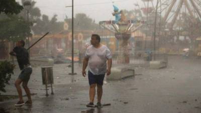 Personas caminan bajo la intensa lluvia durante el paso de la tormenta tropical Fred.