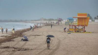 Varias personas aprovechan las olas causadas por la tormenta tropical Isaías, en Miami Beach.
