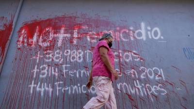 Una mujer camina frente a un aviso pintado en una pared en contra del femicidio hoy en Tegucigalpa (Honduras). EFE/Gustavo Amador