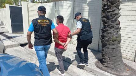 Dos agente de la Interpol tras dar captura al hondureño Oslin Ayala.