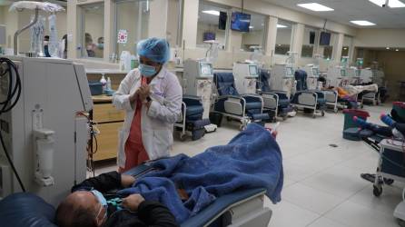 Una enfermera asiste a un paciente mientras recibe su tratamiento de hemodiálisis.