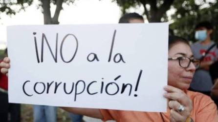 Hondureña sostiene una hoja de papel con la leyenda “¡No a la corrupción!”.