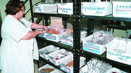 Una trabajadora de Salud busca medicamentos en un almacen.