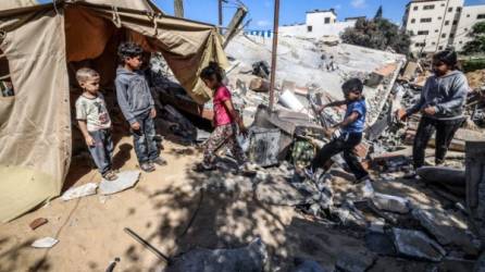 Los niños se reúnen alrededor de una tienda de campaña que Nazmy al-Dahdouh, un palestino de 70 años, instaló sobre las ruinas de su casa, destruida en los recientes ataques aéreos israelíes en la ciudad de Gaza. Foto AFP