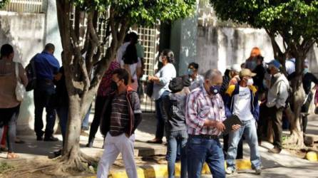 Personas esperan para ser atendidas o para obtener información sobre sus familiares enfermos, frente al Instituto Nacional Cardiopulmonar (Hospital del Tórax) en Tegucigalpa. Foto EFE