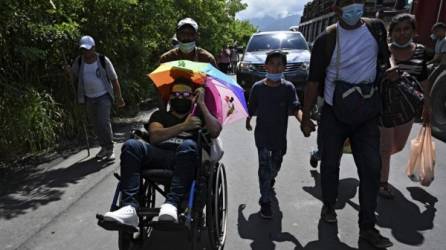 Un migrante hondureño, parte de una caravana que se dirige a Estados Unidos, es empujado en una silla de ruedas en Entre Ríos, Guatemala, luego de cruzar la frontera con Honduras. Foto AFP