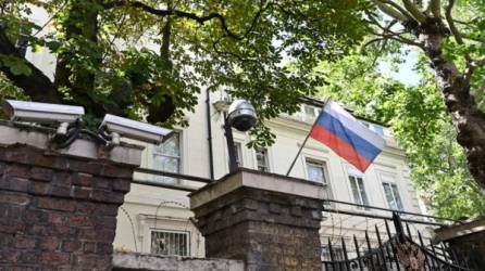 Una bandera rusa ondea frente a las cámaras de vigilancia en la entrada del consulado ruso en Londres. Foto AFP
