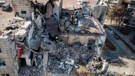 Una vista aérea muestra a los bomberos trabajando entre los escombros de un edificio residencial que fue alcanzado por los escombros de un cohete derribado en Kiev.