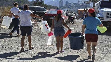 Capitalinos cargan baldes con agua después de obtener agua potable de un camión cisterna en las afueras de Tegucigalpa.