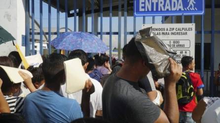 Decenas de personas esperan en la entrada de un parque industrial en Honduras a la espera de meter una hoja de vida para laborar en una maquila.
