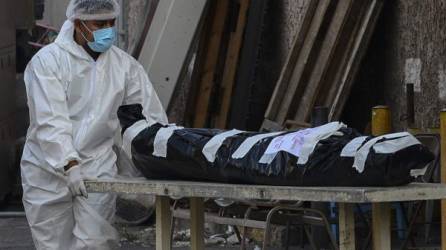 Un trabajador de la salud del Hospital Escuela Universitario transporta el cuerpo de una víctima del covid-19 en Tegucigalpa.