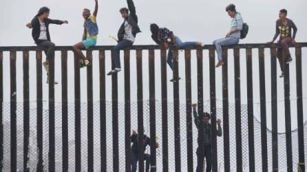 Manifestantes de la caravana suben la valla fronteriza entre Estados Unidos y México durante un mitin. AFP