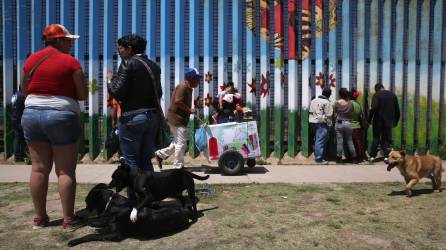 Migrantes se reúnen con sus familiares en México en el muro del parque de la Amistad en la frontera entre ambos países.