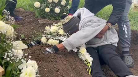 El padre de la niña hondureña llora cuando está siendo sepultada.
