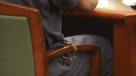Fotografía de archivo de un hombre detenido y esposado a una silla.