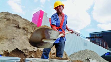 Un trabajador carga cubetas con tierra en una construcción, mientras en una plaza comercial en construcción solicitan albañiles y ayudantes. Fotos: M. Cubas./ M. Valenzuela