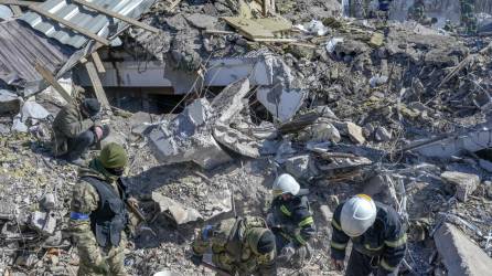 Soldados ucranianos y oficiales de rescate buscan cuerpos entre los escombros en la escuela militar alcanzada por cohetes rusos.
