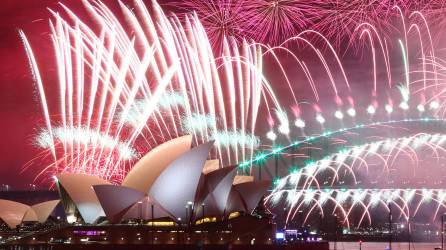 Los fuegos artificiales de Nochevieja iluminan el cielo sobre la Ópera de Sídney y el Puente Harbour durante la exhibición de fuegos artificiales en Sídney el 1 de enero de 2023.