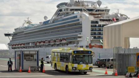 A bus carrying passengers who disembarked from the Diamond Princess cruise ship (back) in quarantine due to fears of the new COVID-19 coronavirus, leaves the Daikoku Pier Cruise Terminal in Yokohama on February 19, 2020. - Relieved passengers began leaving a coronavirus-wracked cruise ship in Japan on February 19 after testing negative for the disease that has now claimed more than 2,000 lives in China. (Photo by Kazuhiro NOGI / AFP)