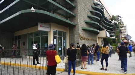Clientes atienden medidas en las afueras de una agencia bancaria en San Pedro Sula. Foto: M. Cubas