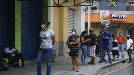 Las autoridades de Salud recomiendan no salir de no ser necesario. Sampedranos hacen fila para entrar a un banco.