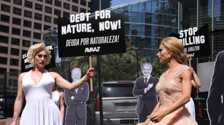 Dos drag queens vestidas de Marilyn Monroe sostienen pancartas junto a las imágenes de los presidentes de Estados Unidos, Joe Biden.