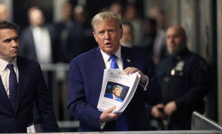 Trump muestra recortes de prensa a la salida de una audiencia en un tribunal de Nueva York.