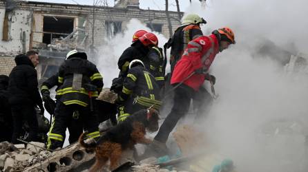 Los miembros de un equipo de búsqueda y recuperación trabajan con un perro de búsqueda en el lugar de un ataque con misiles en Kharkiv el 23 de enero de 2024.