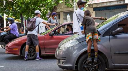 Varios niños y jóvenes migrantes limpian las ventanas de los carros.