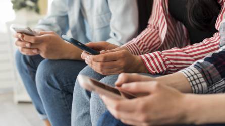 Fotografía referencial de jóvenes utilizando teléfonos celulares.