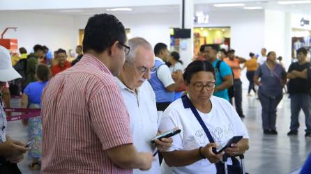 Un agente de servicio al cliente de Aduanas ayuda a estos viajeros a llenar la declaración en línea.