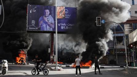 Jóvenes palestinos queman neumáticos durante enfrentamientos con las fuerzas israelíes en la ciudad ocupada de Yenin, en Cisjordania, el 9 de noviembre de 2023.