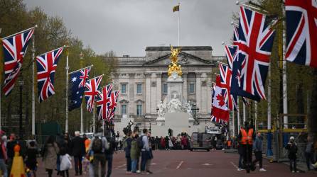 La gente camina bajo las banderas de la Unión y la Commonwealth en The Mall, mirando hacia el Palacio de Buckingham, en el centro de Londres, el 28 de abril de 2023 antes de la ceremonia de coronación de Carlos III y su esposa, Camila, como rey y reina del Reino Unido y Naciones del Reino de la Commonwealth, el 6 de mayo de 2023.