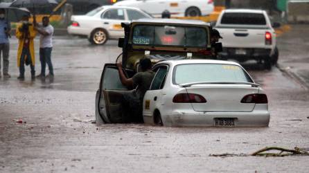 Un conductor de queda varado a mitad de una calle inundada en Tegucigalpa, Honduras.