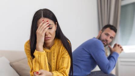 Sad pensive young girl thinking of relationships problems sitting on sofa with offended boyfriend, conflicts in marriage