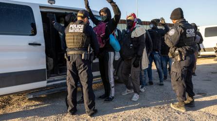 Agentes fronterizos revisan a migrantes antes de procesarlos tras cruzar ilegalmente la frontera sur de EEUU.