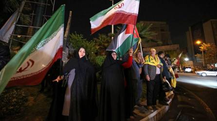 Los manifestantes ondean la bandera de Irán y las banderas palestinas mientras se reúnen en la Plaza Palestina en Teherán el 14 de abril de 2024.