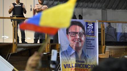 Policías hacen guardia mientras los partidarios del asesinado candidato presidencial ecuatoriano Fernando Villavicencio presentan sus respetos durante un acto organizado por el partido Movimiento Construye y sus amigos en el Centro de Exposiciones de Quito en Quito, el 11 de agosto de 2023.