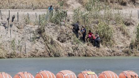 Un grupo de migrantes cruza el río Bravo en la zona donde fueron instaladas una barrera de boyas.