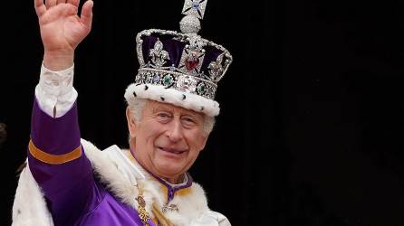 El rey Carlos III de Gran Bretaña, con la corona del estado imperial, saluda desde el balcón del Palacio de Buckingham después de ver el vuelo de la Royal Air Force en el centro de Londres el 6 de mayo de 2023, después de su coronación.