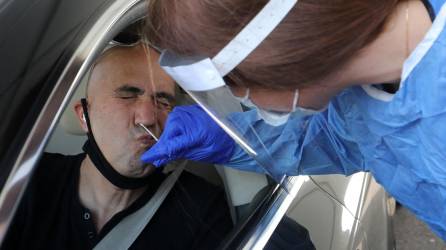 Un médico obtiene una muestra de un hisopo de un hombre en un sitio de prueba para el coronavirus.