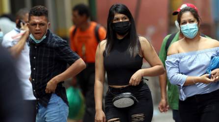 Jóvenes usan la mascarilla mientras caminan en una calle de Honduras.