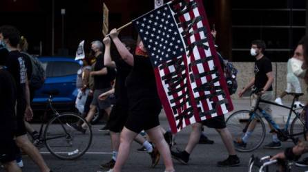 MINNEAPOLIS, MN - JULY 04: A Demonstrator carries an American flag with 'Black Lives Matter' pasted on it during the Black 4th protest on July 4, 2020 in Minneapolis, Minnesota. A number of protest demonstrations occurred around the Twin Cities on Independence Day which were critical of the annual American celebration. Stephen Maturen/Getty Images/AFP
