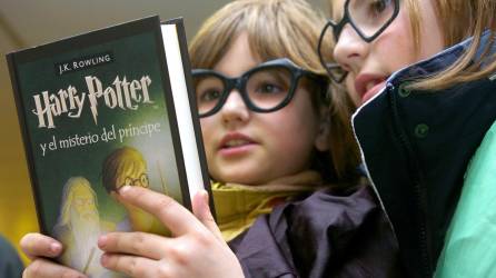Dos pequeñas mientras leen un libro de J. K. Rowling titulado Harry Potter y el misterio del príncipe.