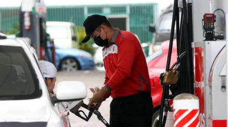 Un empleado de una gasolinera carga de combustible el vehículo de un ciudadano en Honduras.