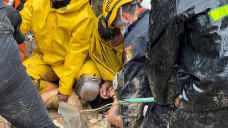Autoridades y miembros de cuerpos de rescate rescatan el cuerpo de una mujer en una zona afectada por un deslizamiento de tierra causado por las fuertes lluvias que afectan la ciudad de Pereira.